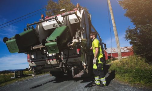 Renovatør som tømmer to plastdunker på renovasjonsbil